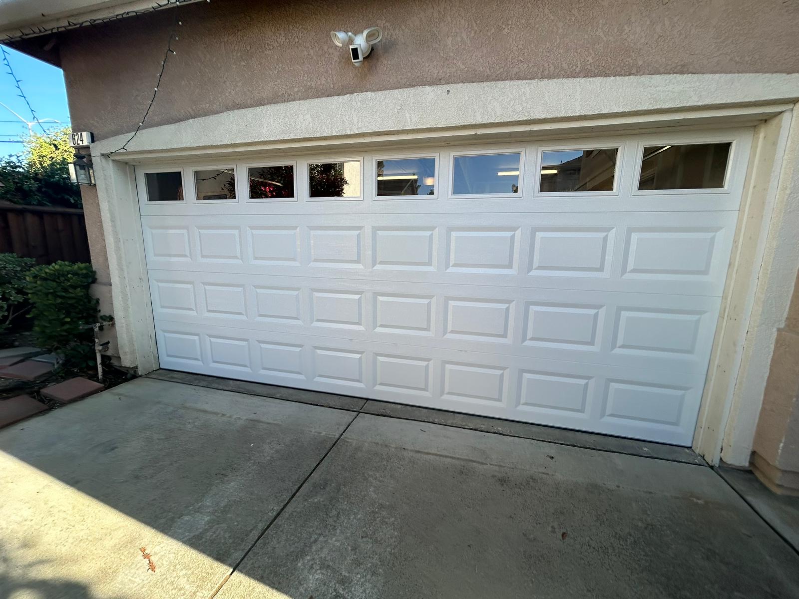 White garage door with windows, residential setting, showcasing quality installation and design, relevant to Graviton construction services.