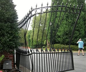 Bent black gate with decorative spikes, positioned in a residential area, illustrating the need for gate repair services.