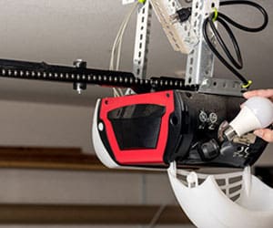 Garage door opener installation with a red and black motor, showcasing the mechanism and wiring, relevant to opener repair and installation services.